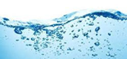 Close-up view of clear blue water with air bubbles rising to the surface, creating a wave-like pattern. The image captures the dynamic motion and clarity of the water, evoking a sense of freshness and purity that parallels a veterinarian's dedication to maintaining health and vitality.