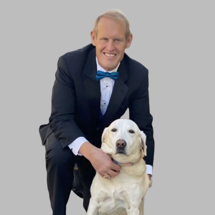 Dr. Brook Niemiec, board certified veterinary dentist, smiling with a yellow Labrador against a gray background.